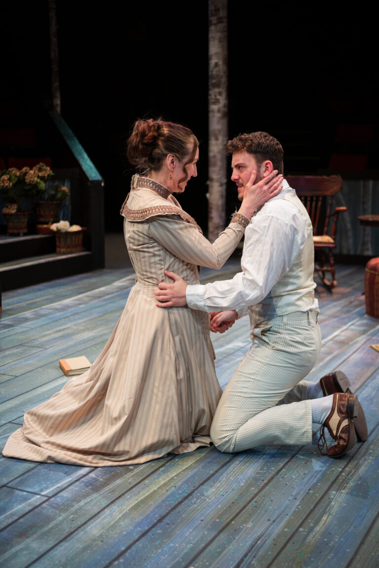 Irina and Trigorin look at each other lustfully, kneeling on the blue plank floor.