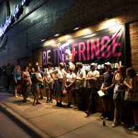 Line of people outside of Theatre in the Round in front of a "Fringe" banner